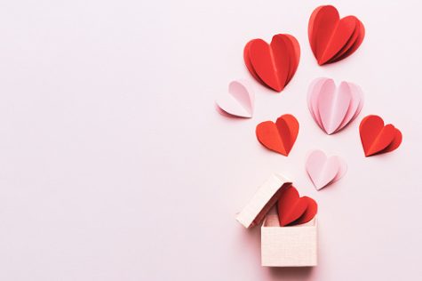 Valentines Day background with red hearts and gift box on pink background with copy space